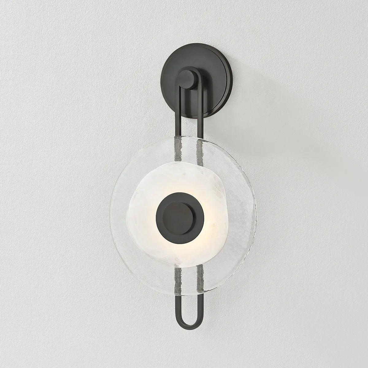 The earring-like design of Keuka Park exudes ornamental, graphic appeal. A thick disc of Blonchino Piastre glass is illuminated at the point where it attaches to the racetrack frame of this striking wall fixture. Whether finished in Aged Brass or Old Bronze, Keuka Park brings modernist artistry to any wall.  Amethyst Home provides interior design, new home construction design consulting, vintage area rugs, and lighting in the Calabasas metro area.