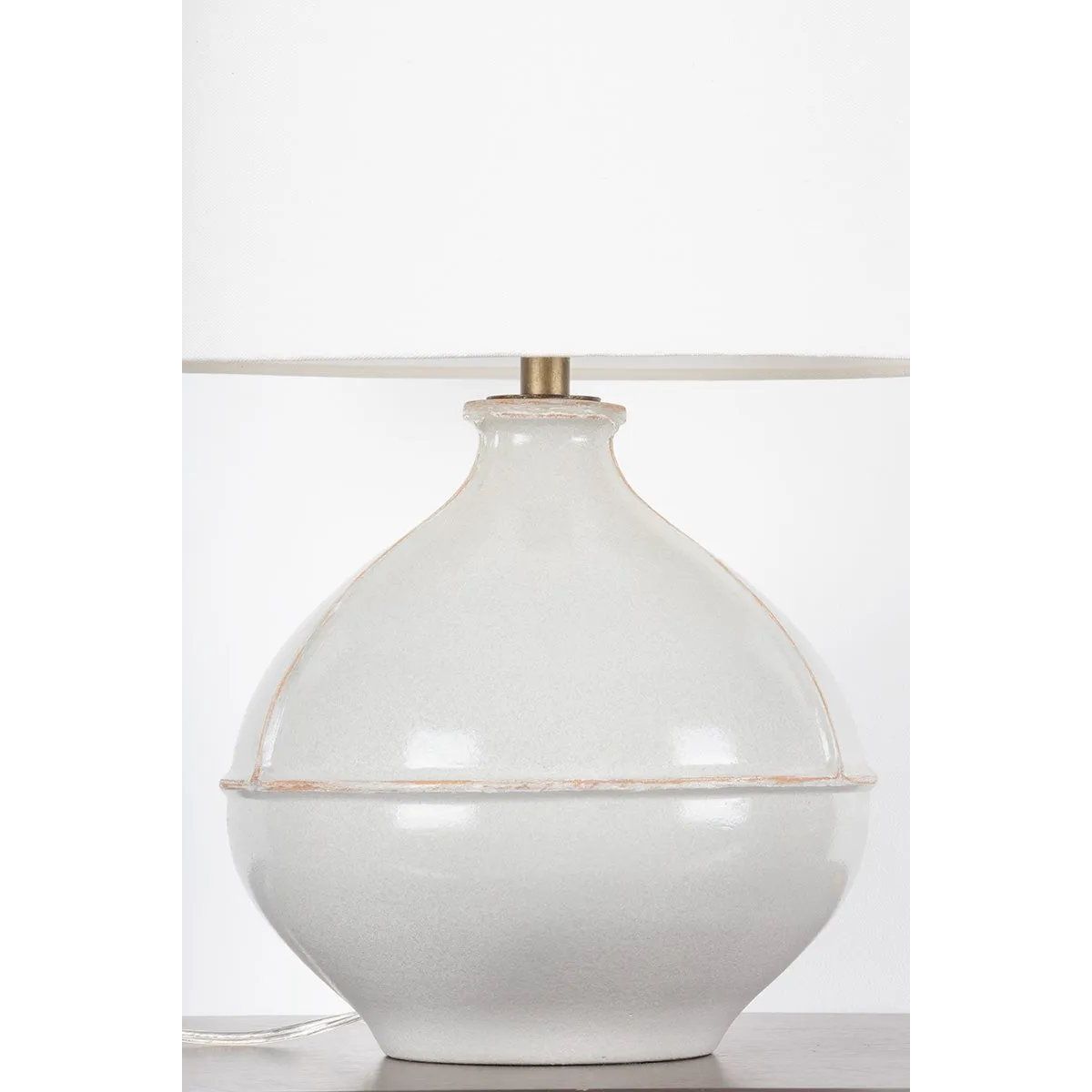 Inspired by rustic pottery, this table lamp's beautifully shaped base is crafted of pale sage ceramic giving it an earthy pale green tone. The off white linen shade pairs naturally and casts a soft glow. Raised seamlines and a reactive glaze that allows hints of the natural ceramic to peek through, give the fixture a hand-thrown, crafted feel. Amethyst Home provides interior design, new home construction design consulting, vintage area rugs, and lighting in the Newport Beach metro area.