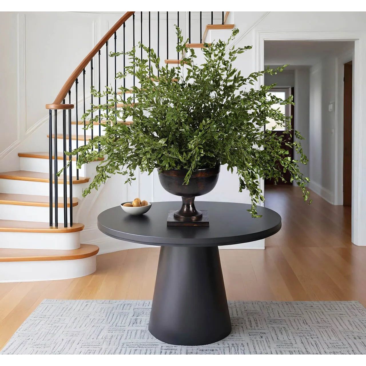 Create a luxurious atmosphere with this green Smilex Branch, housed in a bronze urn. Measuring 51", it's a versatile addition to your living room, bedroom, or entryway, complementing both classic and modern styles. Experience the charm of this arrangement, maintenance-free and ideal for those who love fresh, vibrant decor Amethyst Home provides interior design, new home construction design consulting, vintage area rugs, and lighting in the Washington metro area.