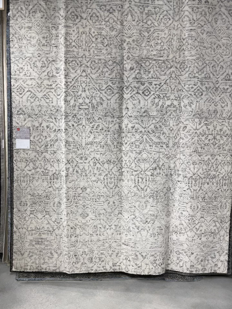Hand-knotted in India of 100% wool, the Amara Ivory/Taupe Area Rug creates a casual yet refined vibe with high-end appeal. With shades of ivory, taupe, and black, this is a gorgeous rug to showcase in your living room, entryway, bedroom, or other high traffic area.   Hand Knotted 100% Wool AMM-04 Ivory/Taupe