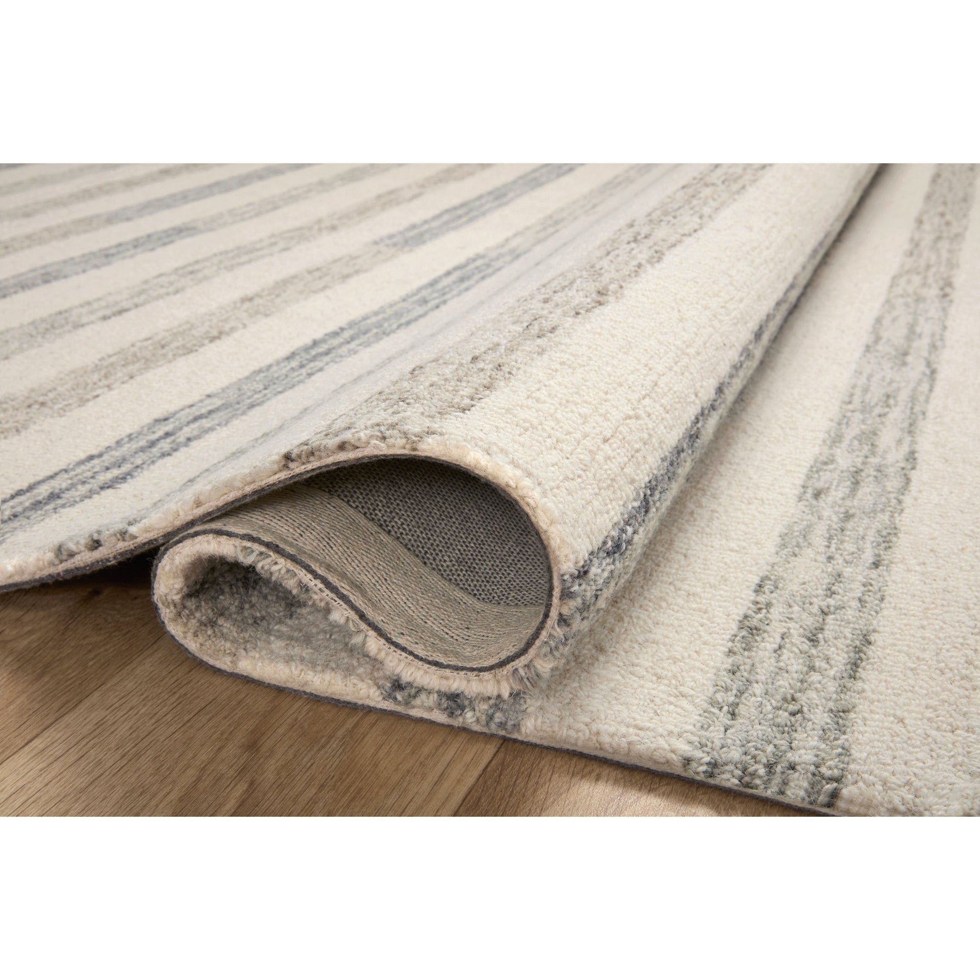 Known for its durability, the Chris Ivory / Slate hooked wool rug is a smart choice for any room in your home that gets lots of love. The subtle, tonal stripes remind us of our favorite California cool hemp rugs. Amethyst Home provides interior design services, furniture, rugs, and lighting in the Dallas metro area.