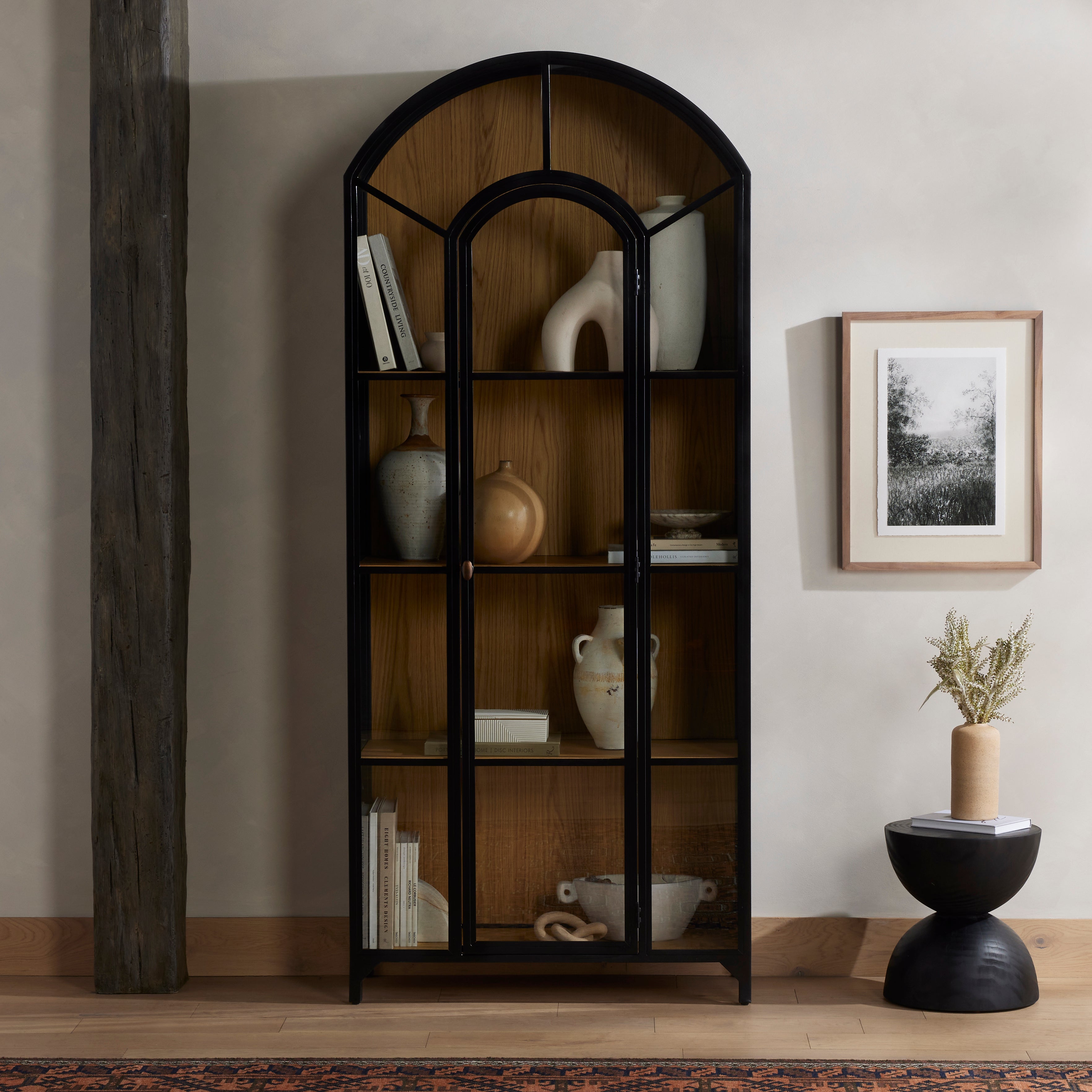 Display barware, books and keepsakes in beautifully arched cabinetry. Solid iron sheeting is finished in a soft, matte black with contrasting brass hardware. Glass fronts allow back paneling of light oak veneer to show, for an eye-catching contrast of color. Amethyst Home provides interior design, new construction, custom furniture, and area rugs in the Omaha metro area.