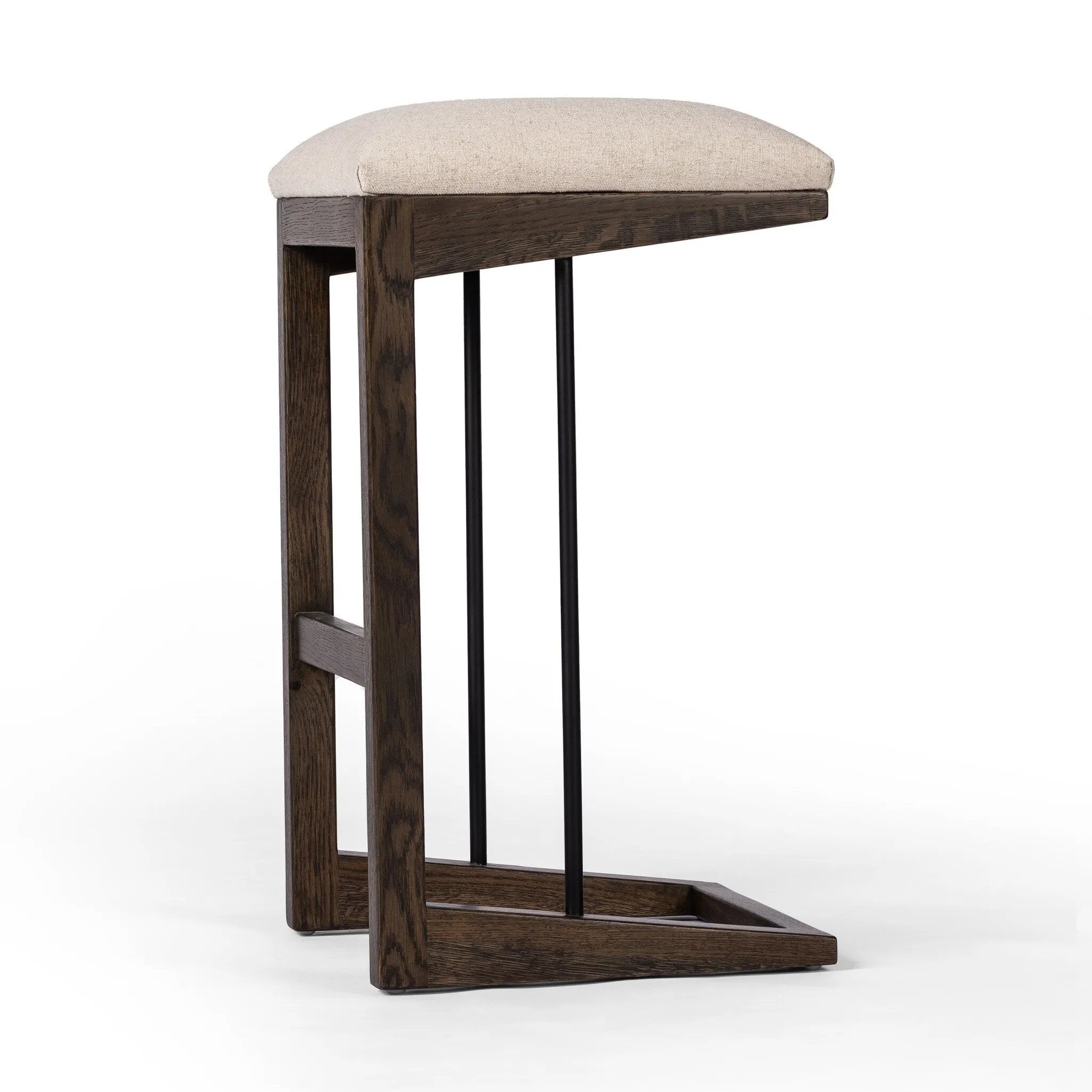 Featuring Finn Sienna Brown Oak Bar Stool by Four Hands at Amethyst Home. A stunner from every angle, this architecturally inspired stool features an angular base crafted from solid oak with two iron rods for added support and visual interest. Seat is upholstered in a linen/cotton/poly blend performance fabric with subtle texture throughout. Performance fab. Amethyst Home provides interior design, new home construction design consulting, vintage area rugs, and lighting in the Nashville metro area.