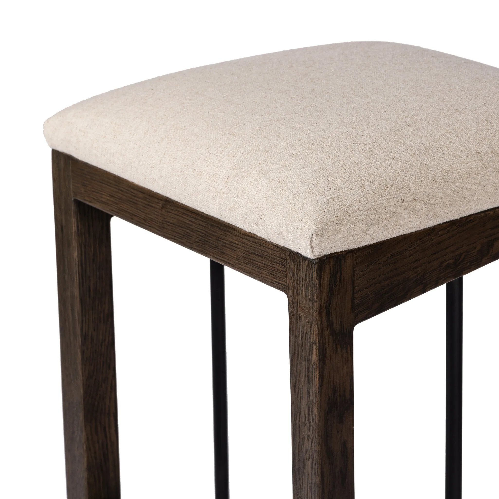 Featuring Finn Sienna Brown Oak Bar Stool by Four Hands at Amethyst Home. A stunner from every angle, this architecturally inspired stool features an angular base crafted from solid oak with two iron rods for added support and visual interest. Seat is upholstered in a linen/cotton/poly blend performance fabric with subtle texture throughout. Performance fab. Amethyst Home provides interior design, new home construction design consulting, vintage area rugs, and lighting in the San Diego metro area.