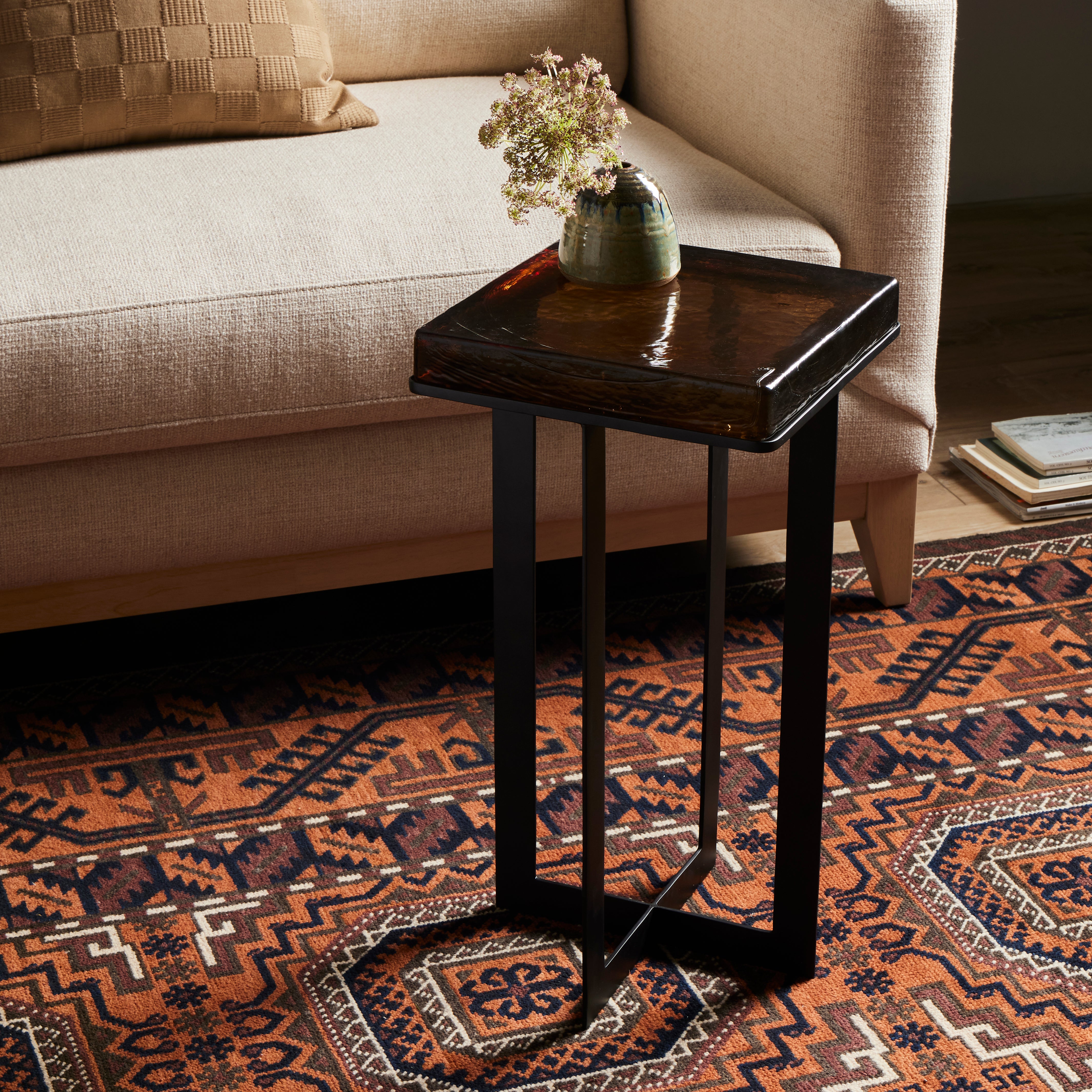 A cradle, angular base of black-finished iron supports a squared tabletop of hand-cast recycled glass in a smoky amber. Perfectly sized to keep your favorite drink or book within reach. Amethyst Home provides interior design, new construction, custom furniture, and area rugs in the Des Moines metro area.