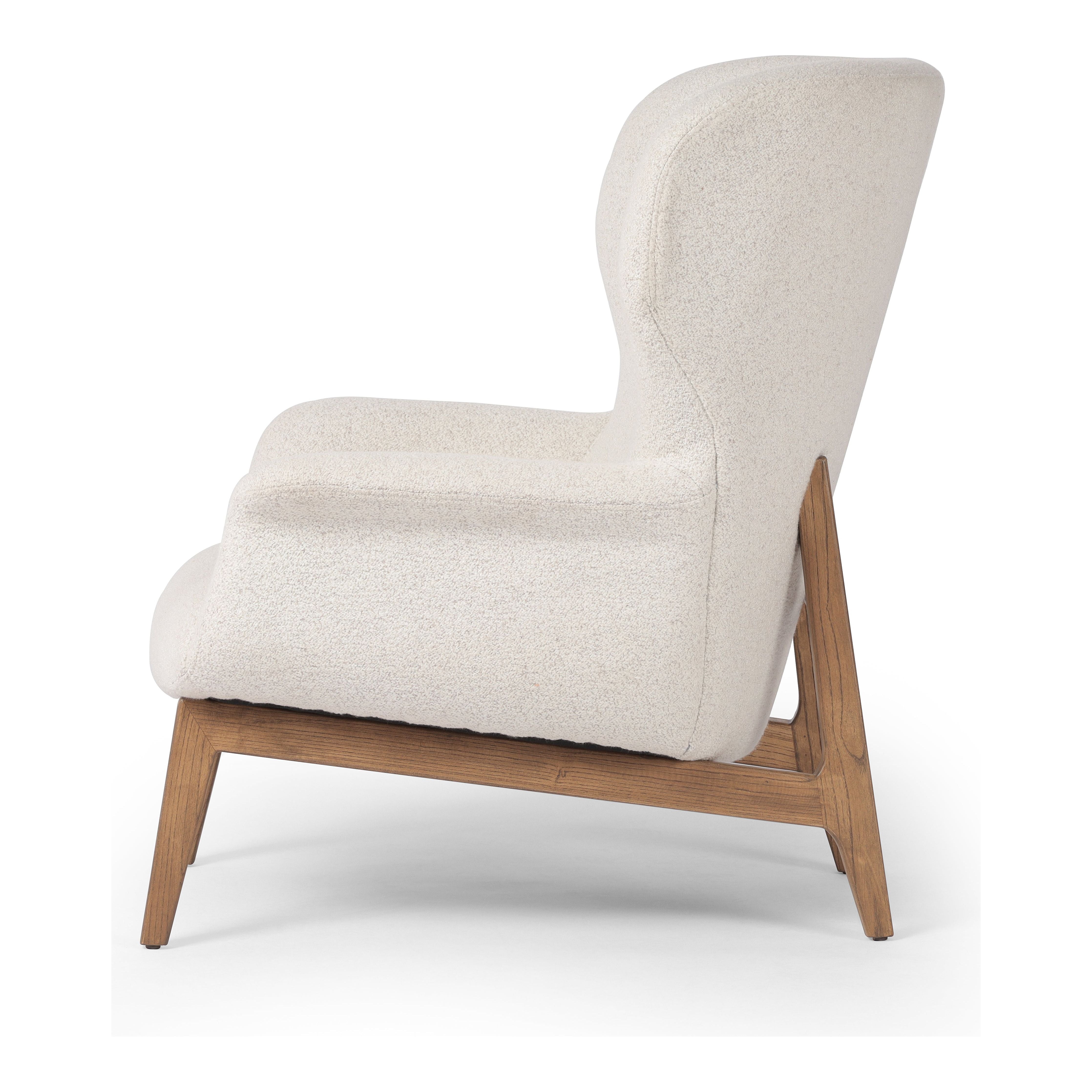 The classic wingback chair is updated with a midcentury-style base. Flared arms and a high winged back with blind tufting offer all-around comfort. Upholstered in a heavily textured boucle performance fabric bringing movement and everyday function to the piece. Amethyst Home provides interior design, new construction, custom furniture, and area rugs in the Charlotte metro area.