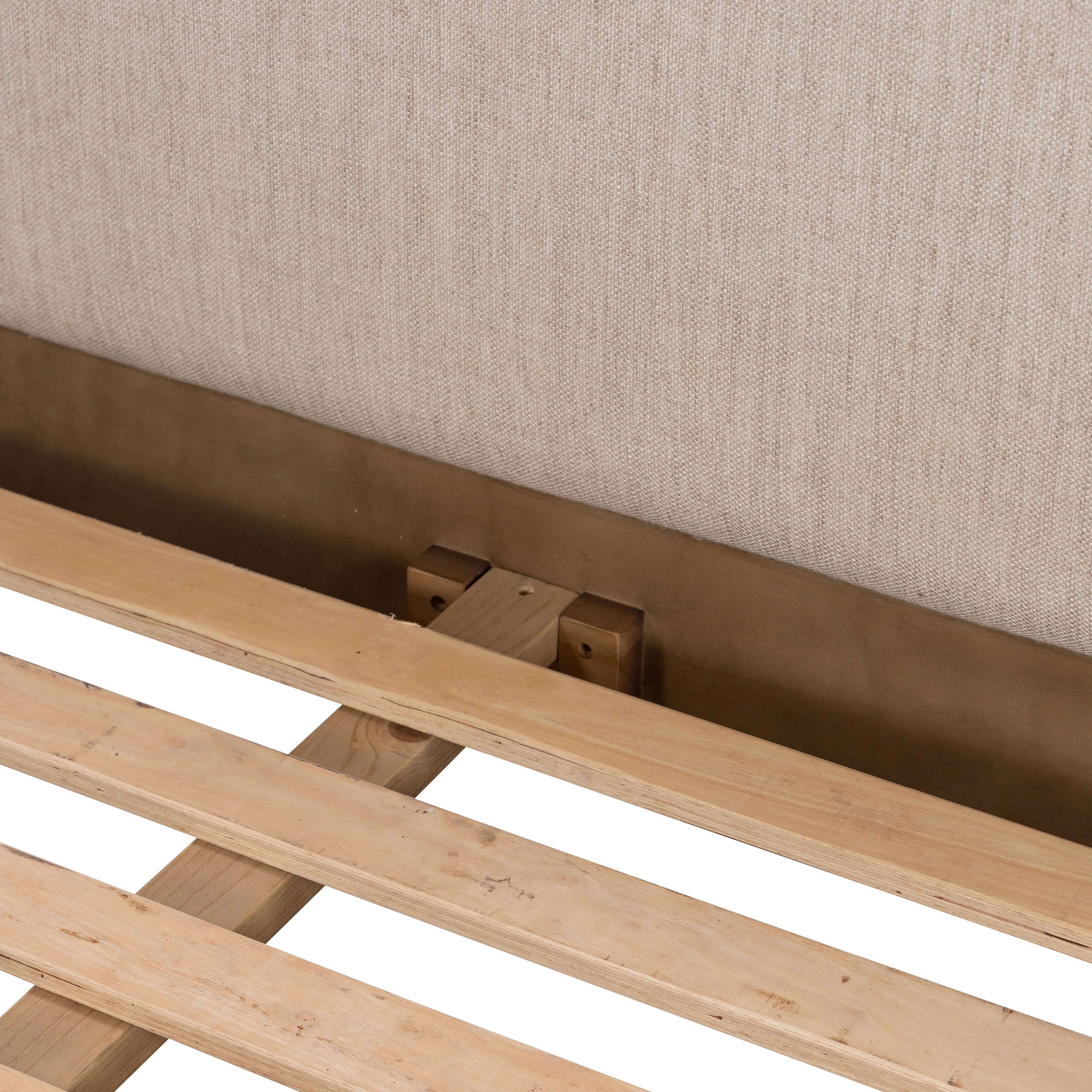 Rounded, chunky dowel legs in an amber oak finish frame the neutral, linen-like upholstered headboard of this bed frame Amethyst Home provides interior design, new home construction design consulting, vintage area rugs, and lighting in the Austin metro area.