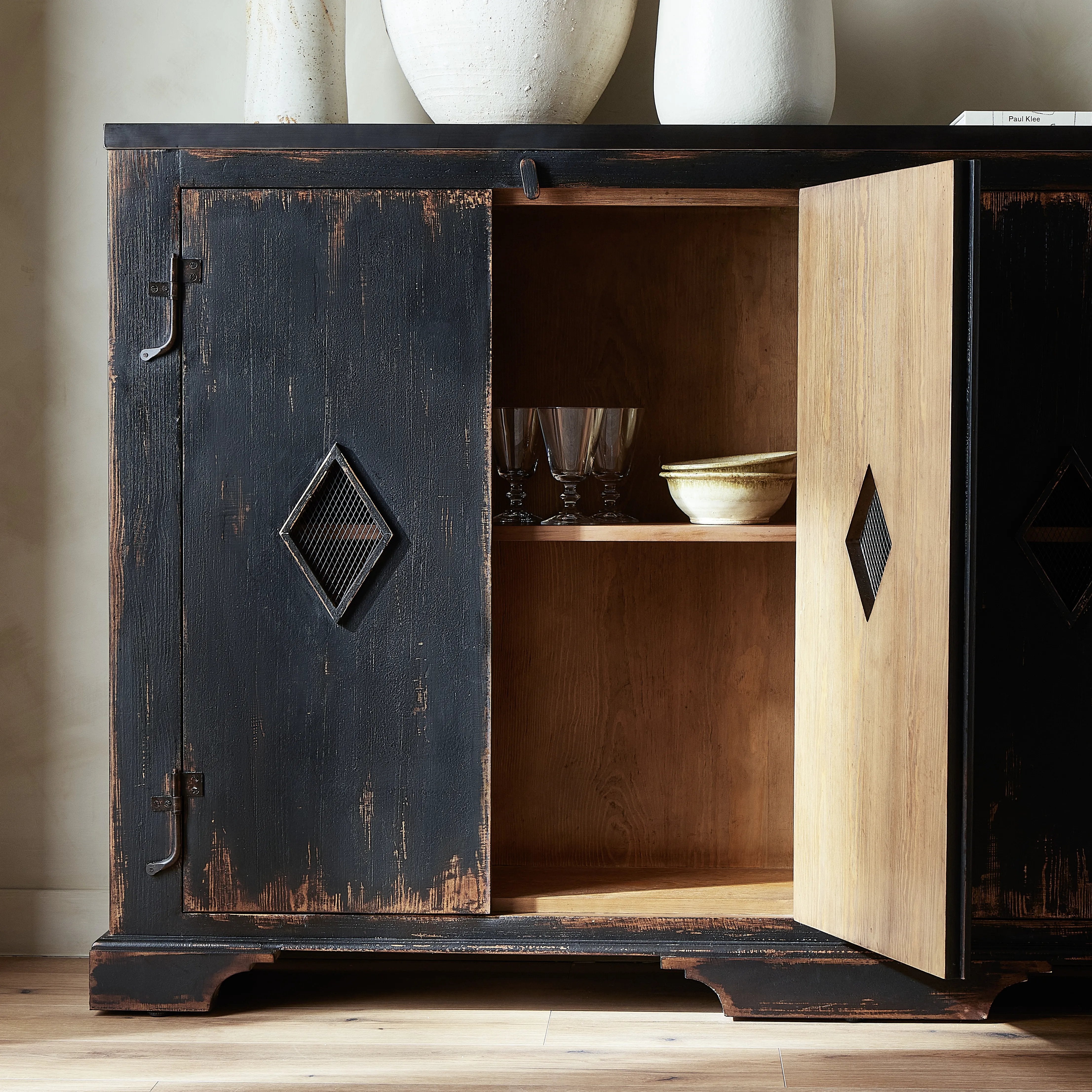 By the makers at Van Thiel, known for their antique-inspired pieces and hand-applied finishes.  This wide but slim solid pine cabinet features door fronts with diamond cutout details and wire mesh inserts. Detailed with antique-inspired hardware and hinges. Metal-clad top in oil-rubbed bronze finish. Amethyst Home provides interior design, new home construction design consulting, vintage area rugs, and lighting in the Seattle metro area.