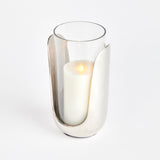 In a marriage of thoughtful design and mixed materials, this stunning hurricane features hand blown glass that slides into a cast aluminum abstract base in a sleek silver. A truly unique contemporary accent for side table, console or mantel. Amethyst Home provides interior design, new construction, custom furniture, and area rugs in the Houston metro area.