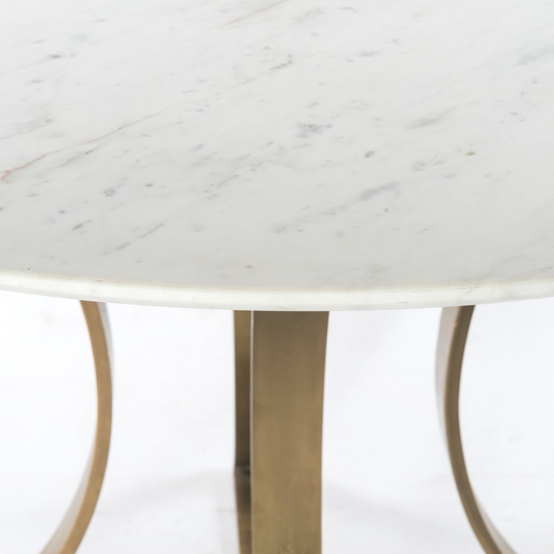 Sophisticated materials take a cue from modern geometry. Cast brass iron forms uniquely-curved angles to balance a contrasting polished white marble top. A refined spin on trend-forward design.  Dimensions: 48"w x 48"d x 30"h, or 60"w x 60"d x 30"h    Colors: Cast Brass, Polished White Marble Materials: Iron, Marble