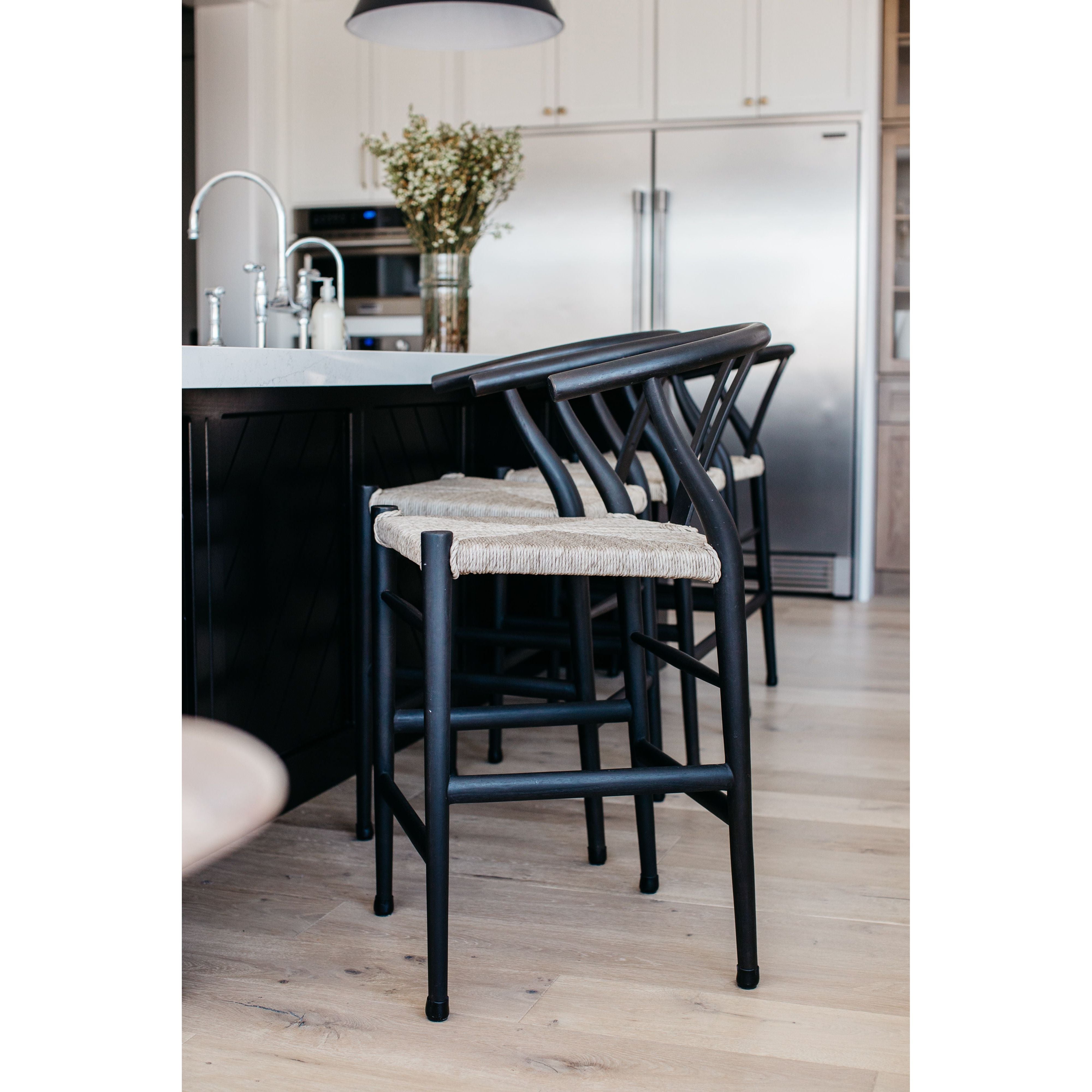 Featuring Muestra Counter + Bar Stool - Black Teak by Four Hands at Amethyst Home. Modern curves redefine the classic wishbone-style of this Muestra Black Teak Counter + Bar Stool. Vintage white all-weather wicker is woven for a dose of fresh texture within weathered grey teak framing. Cover or store indoors during inclement weather and when not in use.
.  Amethyst Home provides interior design, new home construction design consulting, vintage area rugs, and lighting in the Kansas City metro area.