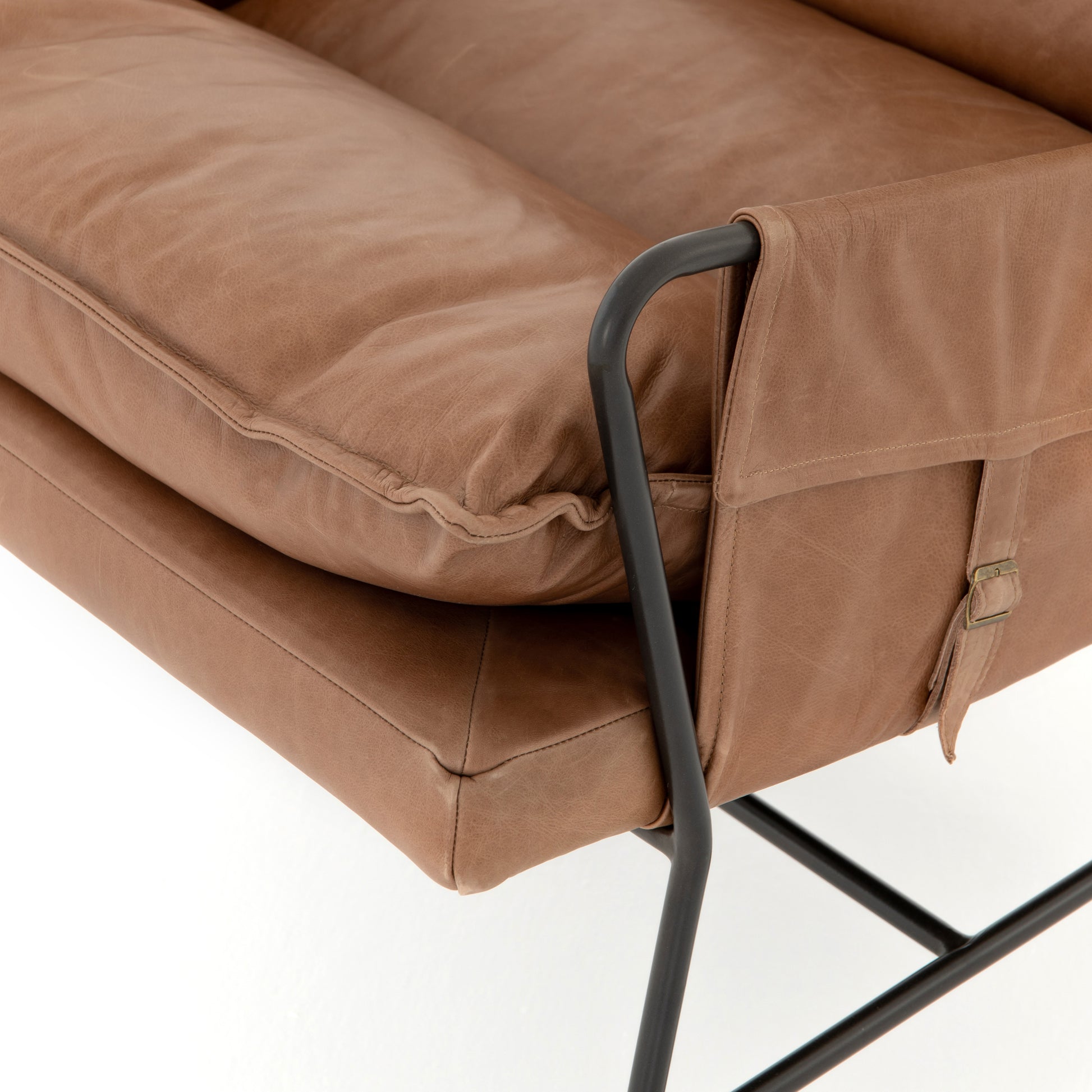 A nod to relaxed modernism, playing up the natural depth of exclusive top-grain leather, with buckle details and low-slung styling crafting the hippest of vibes.  Overall Dimensions: 28.00"w x 37.00"d x 35.00"h Seat Depth: 22" Seat Height: 20" Arm Height from Floor: 23.5" Arm Height from Seat: 3.5"  Colors: Waxed Ebony, Chaps Saddle Materials: Iron, Top Grain Leather