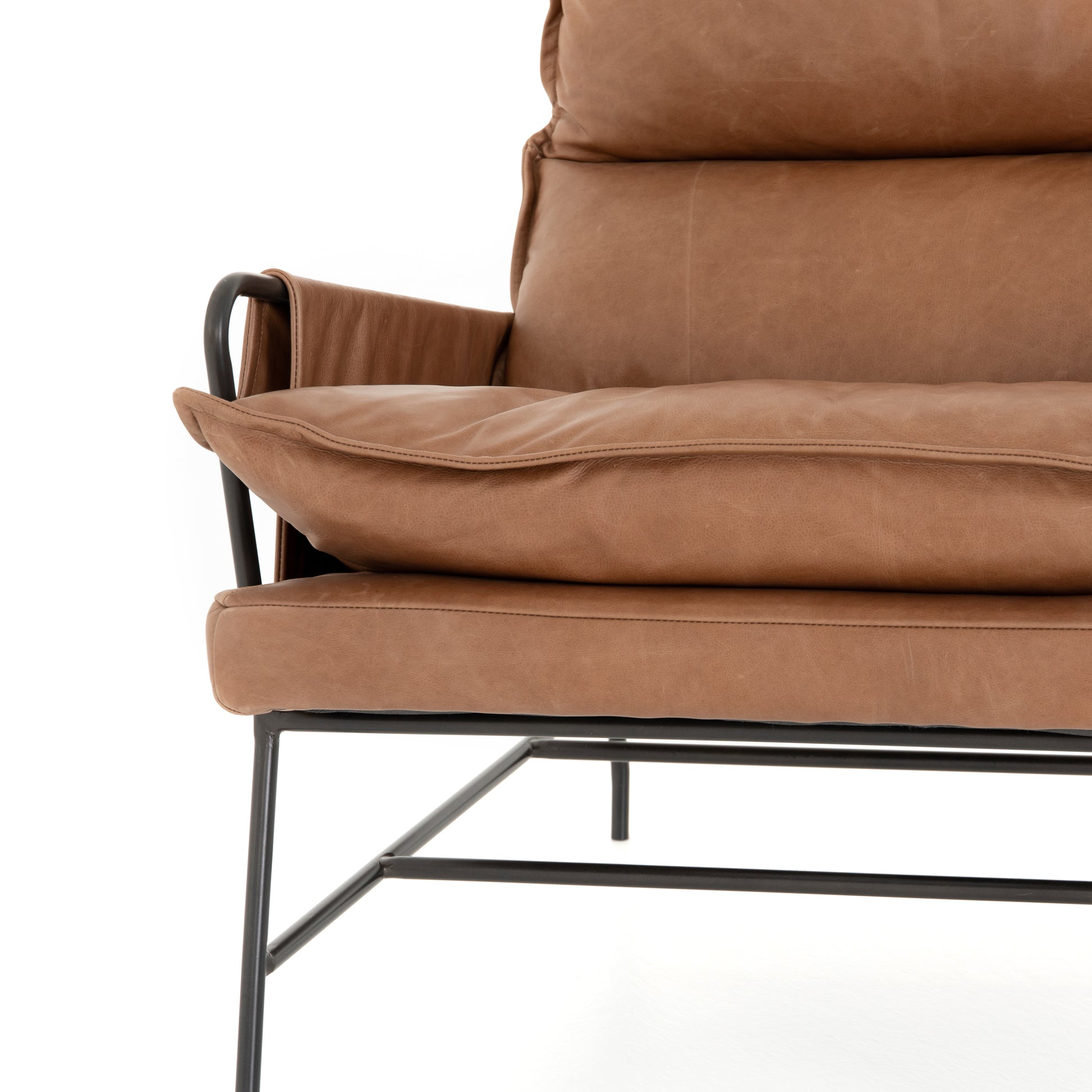 A nod to relaxed modernism, playing up the natural depth of exclusive top-grain leather, with buckle details and low-slung styling crafting the hippest of vibes.  Overall Dimensions: 28.00"w x 37.00"d x 35.00"h Seat Depth: 22" Seat Height: 20" Arm Height from Floor: 23.5" Arm Height from Seat: 3.5"  Colors: Waxed Ebony, Chaps Saddle Materials: Iron, Top Grain Leather