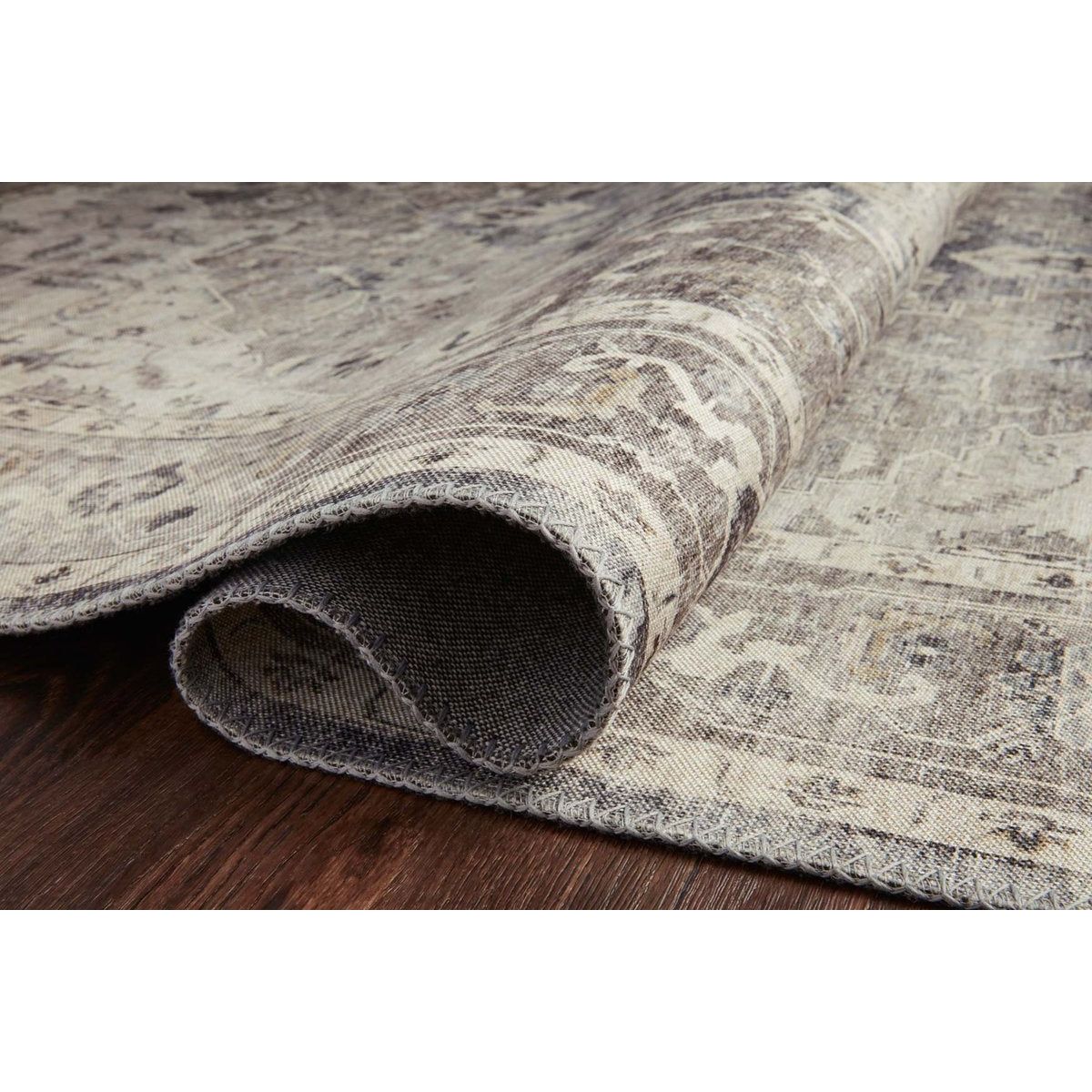 Featuring soft motifs in a carefully curated color palate of grey, black, ivory and hints of blue, the Hathaway Steel / Ivory area rug captures the essence of one-of-a-kind vintage or antique area rug at an attractive price.