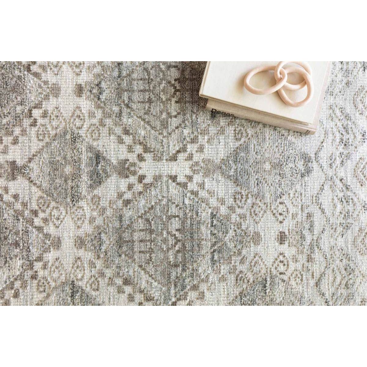 The Idris Stone area rug from Loloi is meticulously hand-knotted of viscose and wool. You will love this rug because the rug is:  Perfect for entryways, living rooms, and bedrooms Easy to clean and maintain Gorgeous with the intricate pattern and patina Warms up any room with the high / low pile Hand-Knotted 70% Viscose | 30% Wool ID-01 Stone